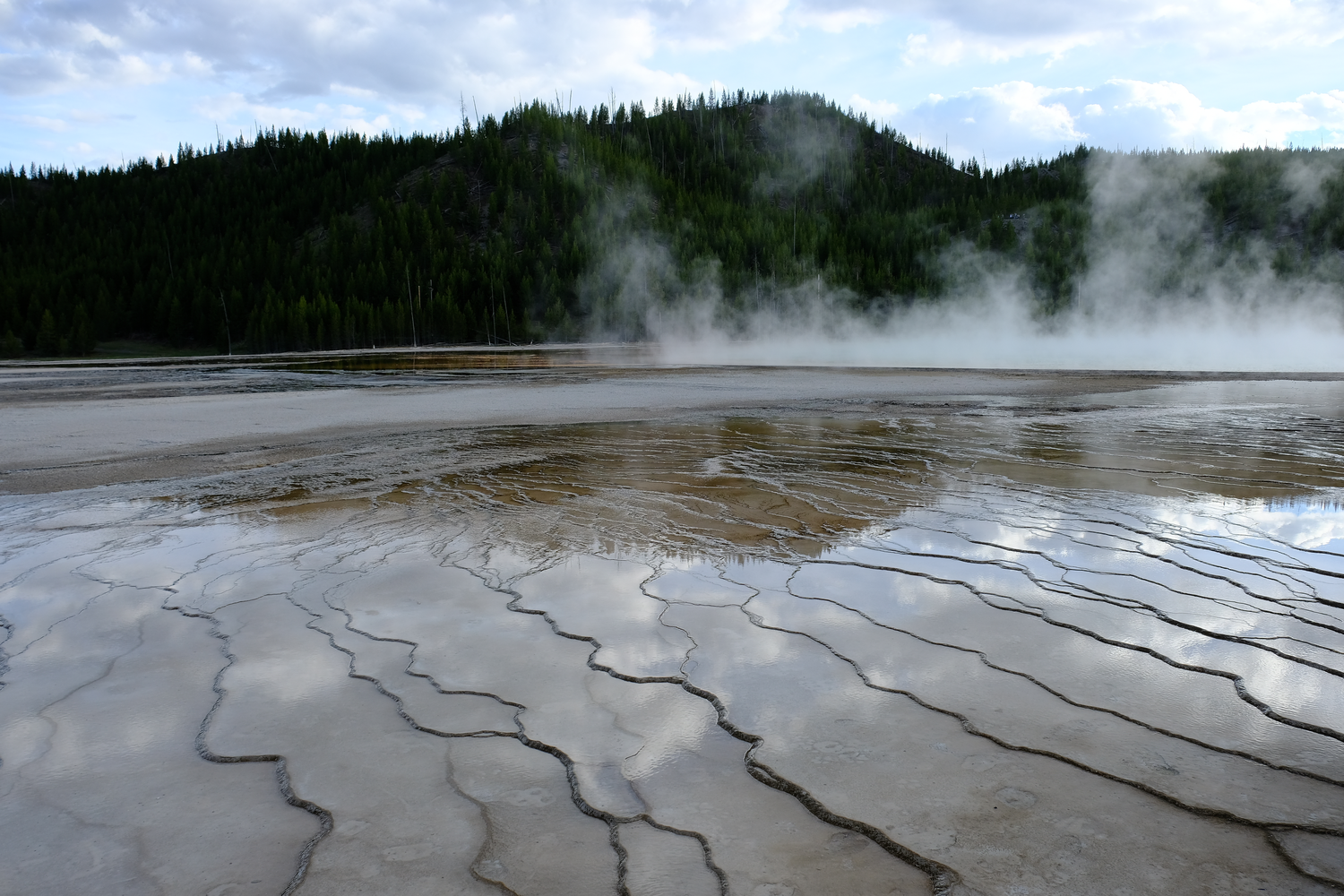 Photo of runoff of water from a nearby geyser, reflecting the sky, in Yellowstone National Park.