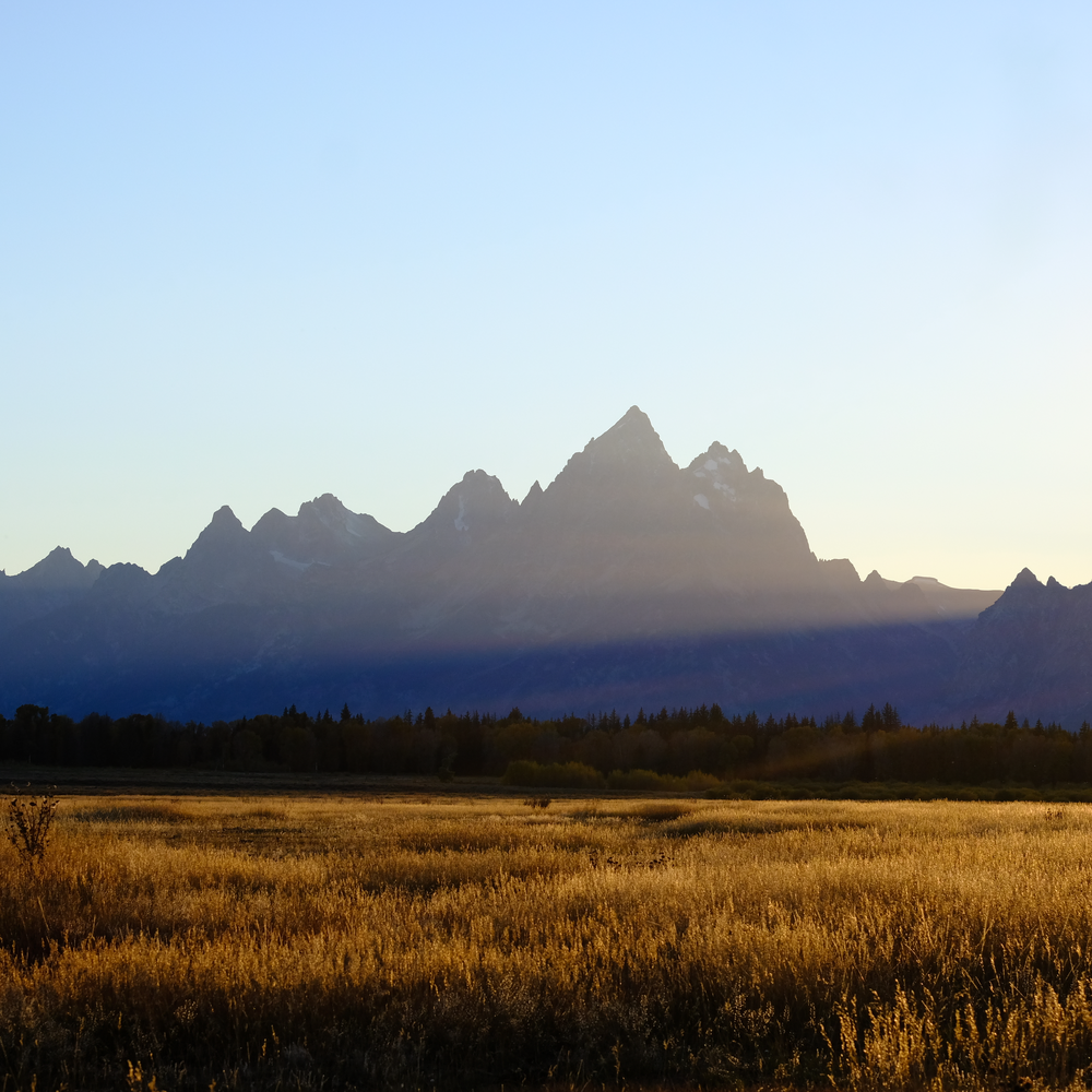 Photo of the Grand Teton Mountain Range within Grand Tetons National Park at sunset.